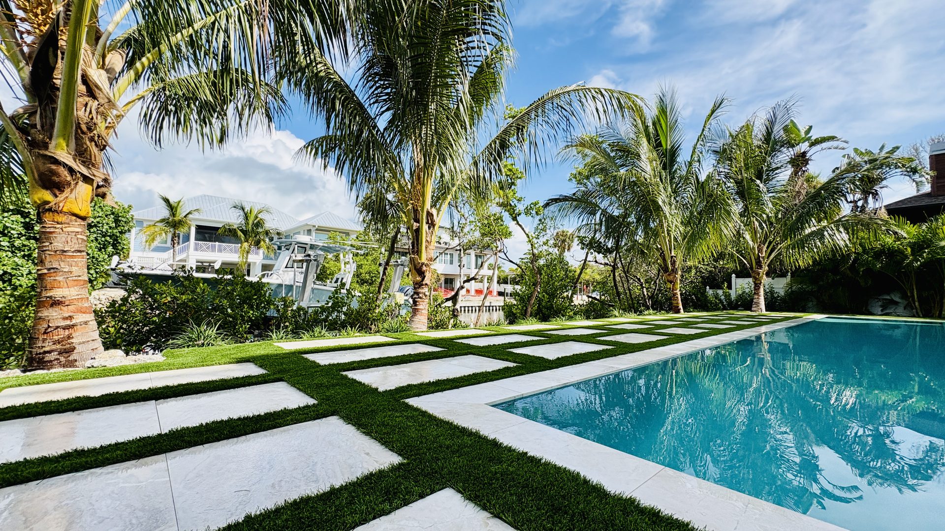 Luxury Florida backyard with grid pavers, artificial turf, and pool by Empire Greens